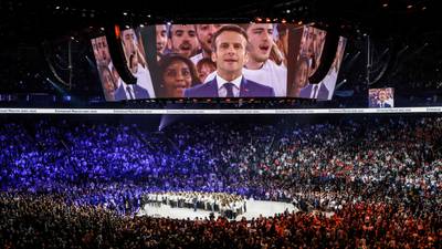 Emmanuel Macron sings the French national anthem as he appears on a giant screen at the end of his first campaign meeting at the Paris La Defence Arena in Nanterre. AFP