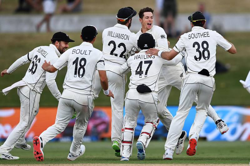 New Zealand bowler Mitchell Santner is mobbed by teammates after taking a catch to dismiss Pakistan's Naseem Shah and clinch his team's victory. AP