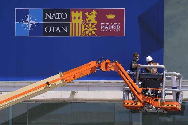 Workers on a crane put up Nato posters on Saturday ahead of the alliance's summit in Madrid. AP Photo