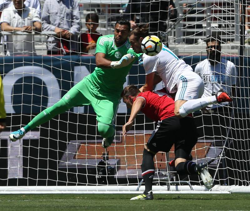 Manchester United goalkeeper Sergio Romero, left, attempts to block a shot while defender Phil Jones and Real Madrid forward Gareth Bale collide. Beck Diefenbach / AFP