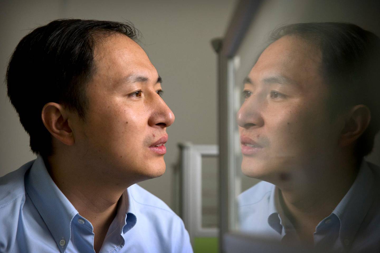In this Oct. 10, 2018 photo, He Jiankui is reflected in a glass panel as he works at a computer at a laboratory in Shenzhen in southern China's Guangdong province. Chinese scientist He claims he helped make world's first genetically edited babies: twin girls whose DNA he said he altered. He revealed it Monday, Nov. 26, in Hong Kong to one of the organizers of an international conference on gene editing. (AP Photo/Mark Schiefelbein)
