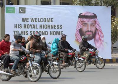 Pakistani motorcyclists pass by a banner welcoming Mohammed bin Salman in Lahore. AP Photo