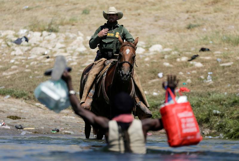 A US Border Patrol officer blocks the path of a migrant trying to return to the US after having crossed into Mexico. Reuters