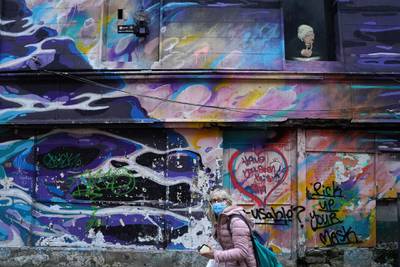 A woman walks past writing on a wall reading 'pick up your mask' during the government's highest level of lockdown restrictions in Galway, Ireland. Reuters