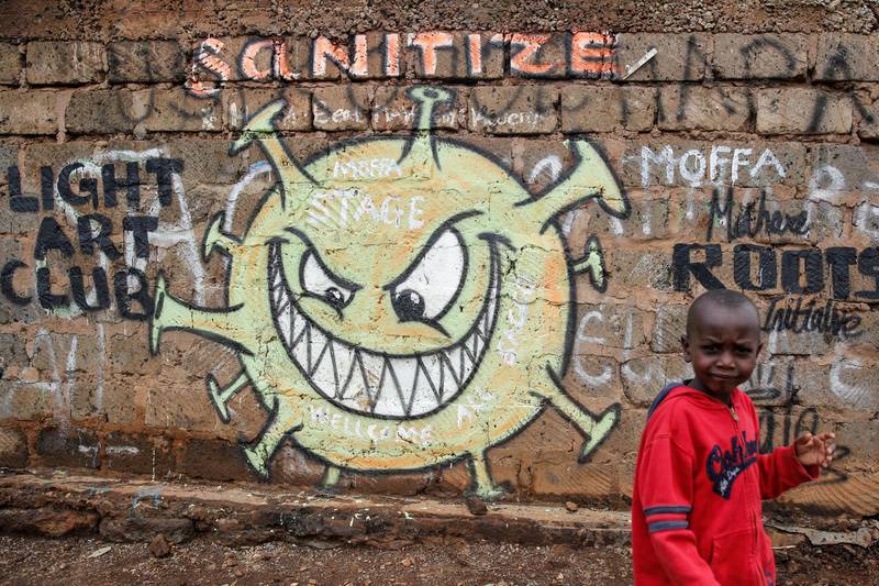 A child walks past an informational mural depicting the new coronavirus and warning people to sanitize to prevent its spread, painted by graffiti artists from the Mathare Roots youth group, in the Mathare informal settlement, of Nairobi, Kenya, Wednesday, April 22, 2020. (AP Photo/Brian Inganga)