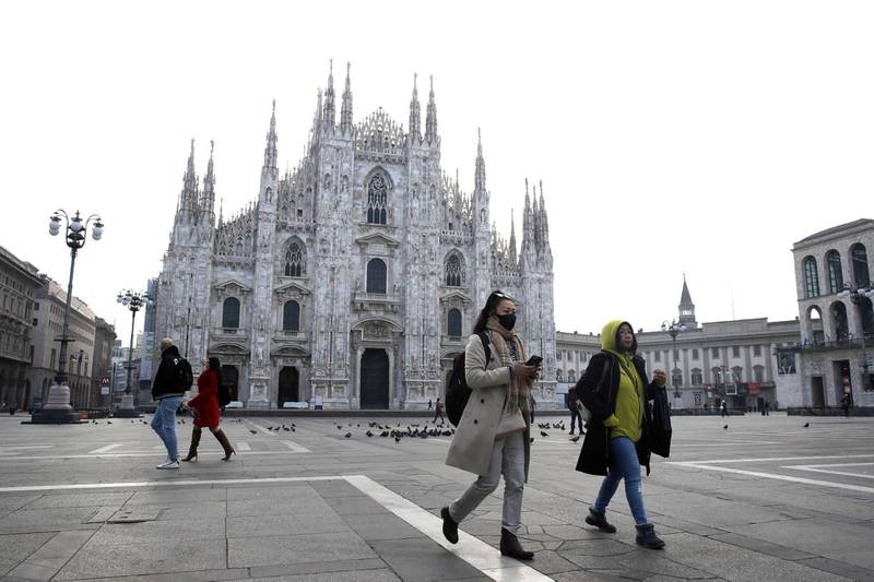 FILE - In this Sunday, Feb. 23, 2020. file photo, a woman wearing a sanitary mask walks past the Duomo gothic cathedral in Milan, Italy. The focal point of the coronavirus emergency in Europe, Italy, is also the region's weakest economy and is taking an almighty hit as foreigners stop visiting its cultural treasures or buying its prized artisanal products, from fashion to food to design. Europeâ€™s third-largest economy has long been among the slowest growing in the region and is the one that is tallying the largest number of virus infections outside Asia. (AP Photo/Luca Bruno, File)
