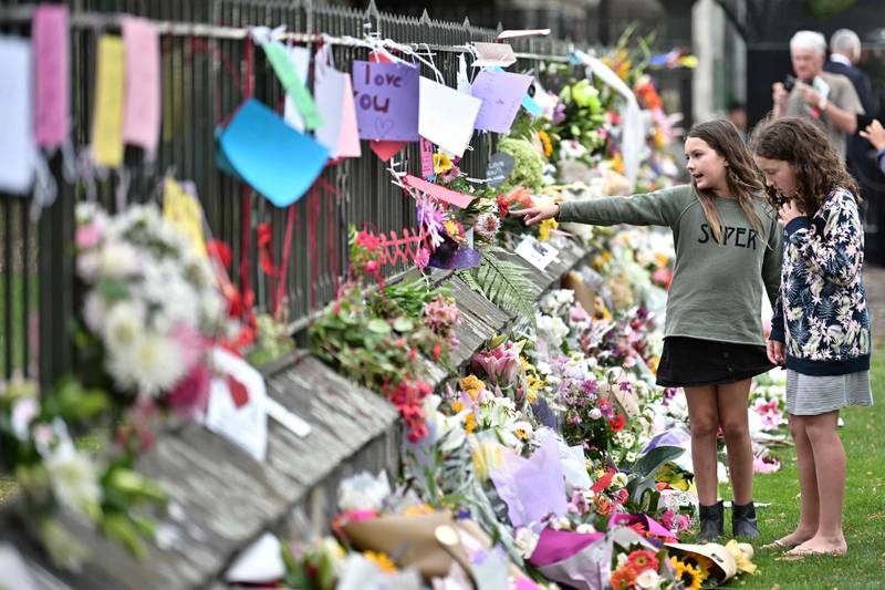 Girls look at messages of support and flowers lain in tribute to victims of the mosque attacks in Christchurch. AFP