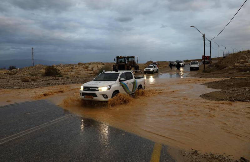 A security vehile drives through flood water running across a road near Kibutz Ein Gegi in the Judean desert following heavy rainfall in the Jerusalem area on January 9, 2020.  A stormy weather including high winds and heavy rainfall, lashed Israel and the Palestinian territories. / AFP / MENAHEM KAHANA
