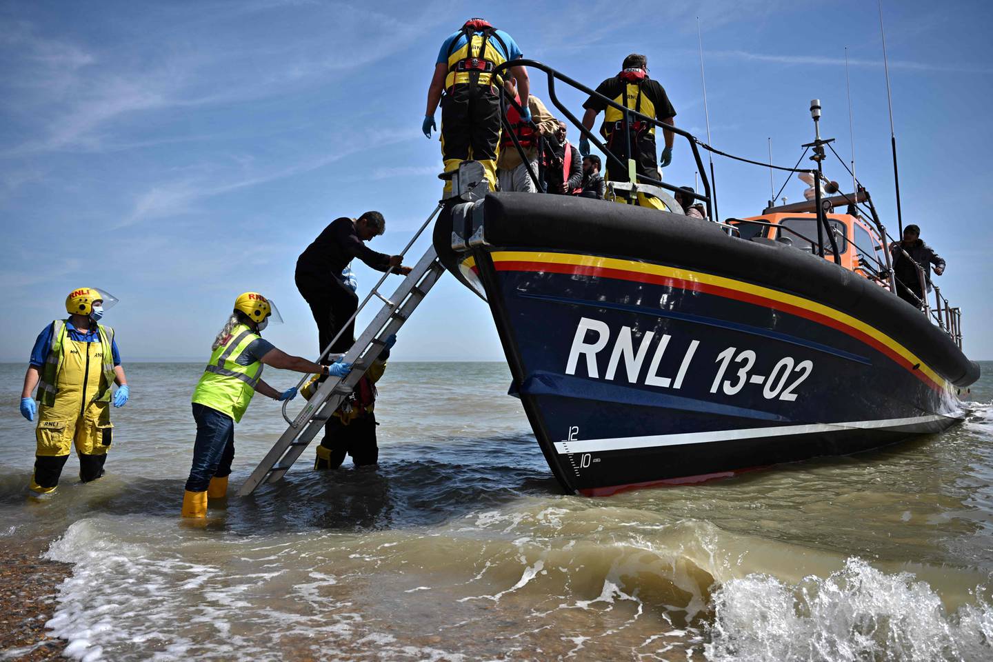 British rescuers help migrants off a boat after being picked up trying to cross the English Channel.  AFP 