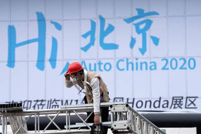 A worker labors near a sign which reads "Hi Beijing, Auto China 2020" ahead of the Auto China 2020 show to be held in Beijing. AP Photo