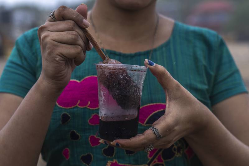 A girl prepares to drink shaved ice at Juhu beach in Mumbai. AP
