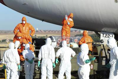 Several paramedics, wearing protective suits, move Spanish missionary Miguel Pajares, who is infected with Ebola, into an ambulance upon his arrival at Spanish Air Force base in Torrejon de Ardoz, outside Madrid. Spanish Defence Military / EPA