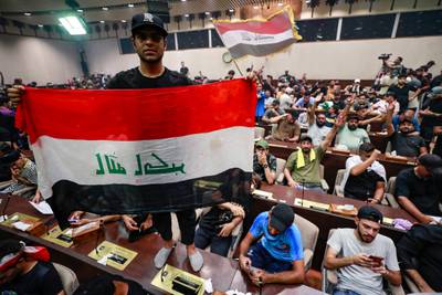 Demonstrators wave Iraqi flags and pictures of Mr Al Sadr inside the legislature.  AFP