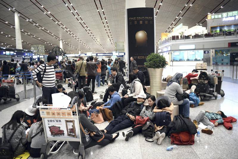 Passengers rest as they wait for their flights at the Beijing Capital International airport, on November 23, 2015, after heavy snowstorm cancelled and delayed numerous flights in Beijing. AFP PHOTO / GOH CHAI HIN (Photo by GOH CHAI HIN / AFP)