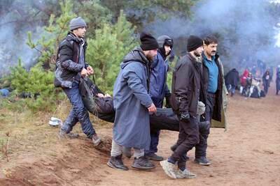 Migrants carry someone who has fallen ill. AP