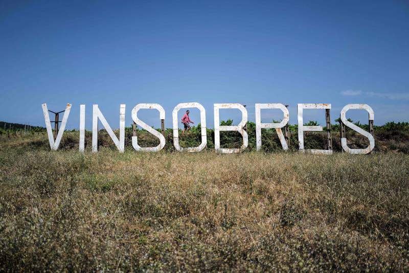 Cedric Guillaume-Corbin walks behind a giant sign on a hillside in Vinsobres, in the Rhone Valley, south eastern France.