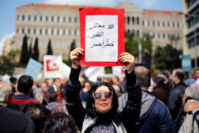 A protester holds a placard with Arabic that reads, "Salary of the poor is a red line," in front of the government building during a parliament session to approve a plan to restructure the country's electricity sector, in Beirut, Lebanon, Wednesday, April 17, 2019. State employees fear they could have their salaries cut as the government discusses austerity measures to avoid a financial and economic crisis. (AP Photo/Bilal Hussein)