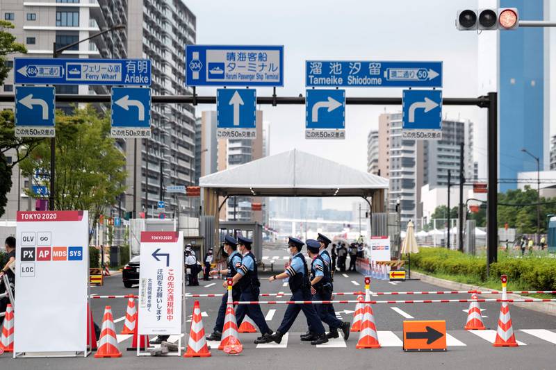 Policemen walk past one of the entrances to the Olympic Village in Tokyo.