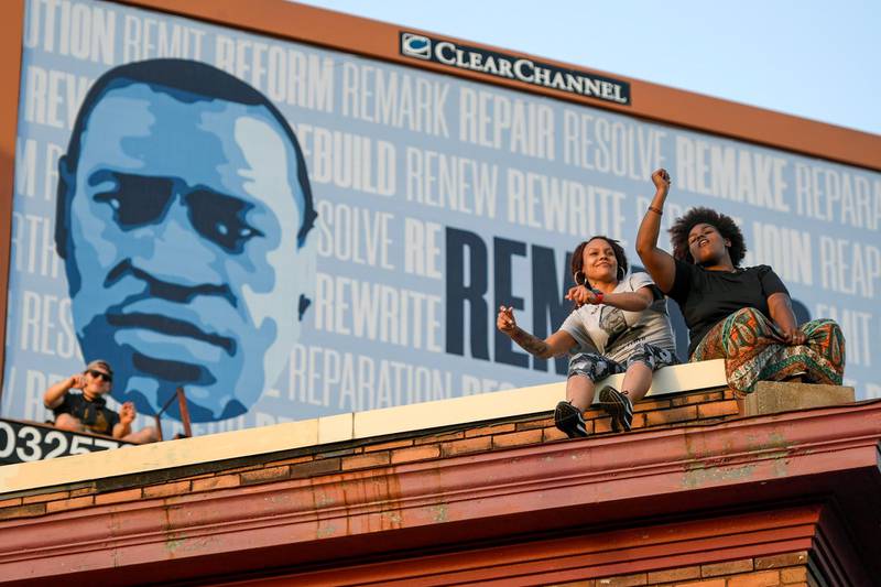 Two women sit on a roof as they listen to a memorial music performance, at George Floyd Square, in Minneapolis. EPA