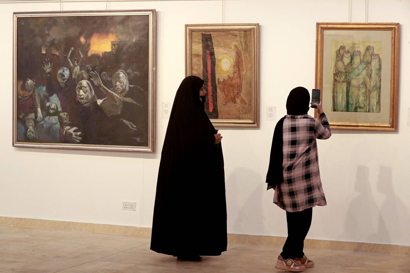 Visitors look at paintings by renowned artist Faiq Hassan, on display at Iraq's Ministry of Culture, in Baghdad on April 6, 2022. AFP