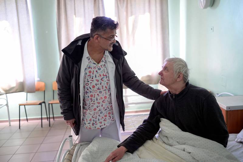 Syrian doctor Ossama Jari  (L) examines a patient in a hospital in Mykolaiv, on March 12, 2022.  - Jari is a Syrian doctor who flee from war from Damascus to Ukraine, now caught by another war.  (Photo by BULENT KILIC  /  AFP)