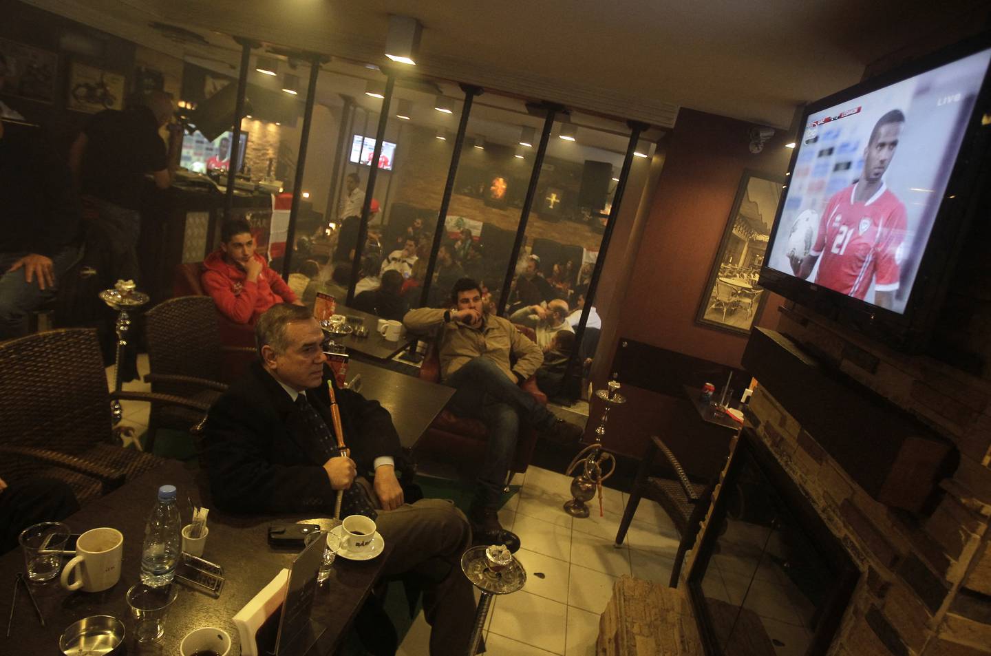 Lebanese men watch on television the Asian soccer team's 2014 World Cup qualifier between Lebanon and the UAE at a cafe in Beirut February 29, 2012. Lebanon advanced to the next round despite losing 4-2.  AFP PHOTO/JOSEPH EID (Photo by JOSEPH EID / AFP)