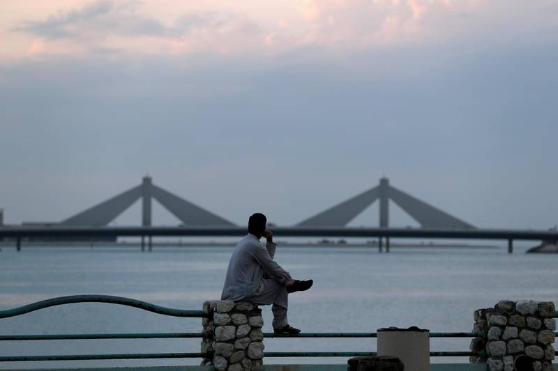 FILE PHOTO: A man sits and looks towards the Sheikh Isa Causeway, linking Diplomatic Area to Muharraq, during the early evening hours in Manama, Bahrain, November 11, 2018. Picture taken November 11, 2018. REUTERS/Hamad I Mohammed -/File Photo