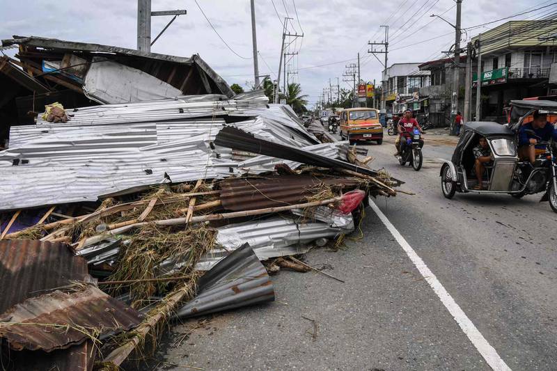 Motorists pass a destroyed house in the aftermath of the typhoon. AFP