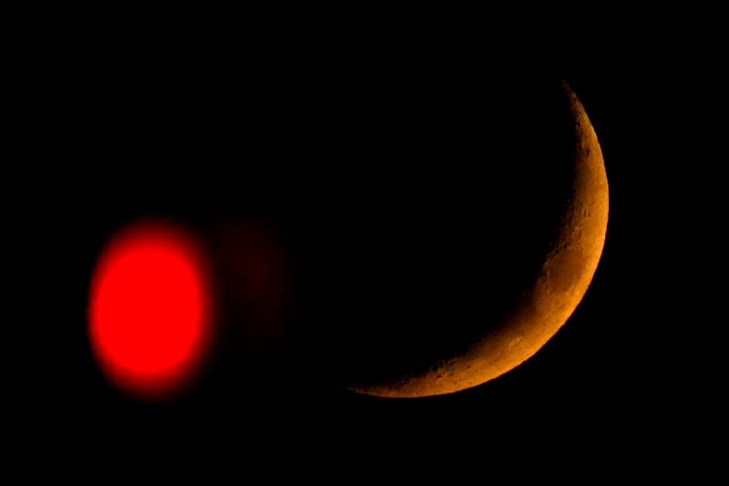 The crescent moon sets beyond a stop light in Overland Park, Kansas. AP