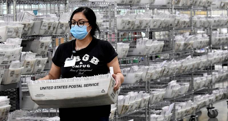 A worker carries ballots that are postmarked and mailed by the deadline on election day in Pomona, California. AP Photo