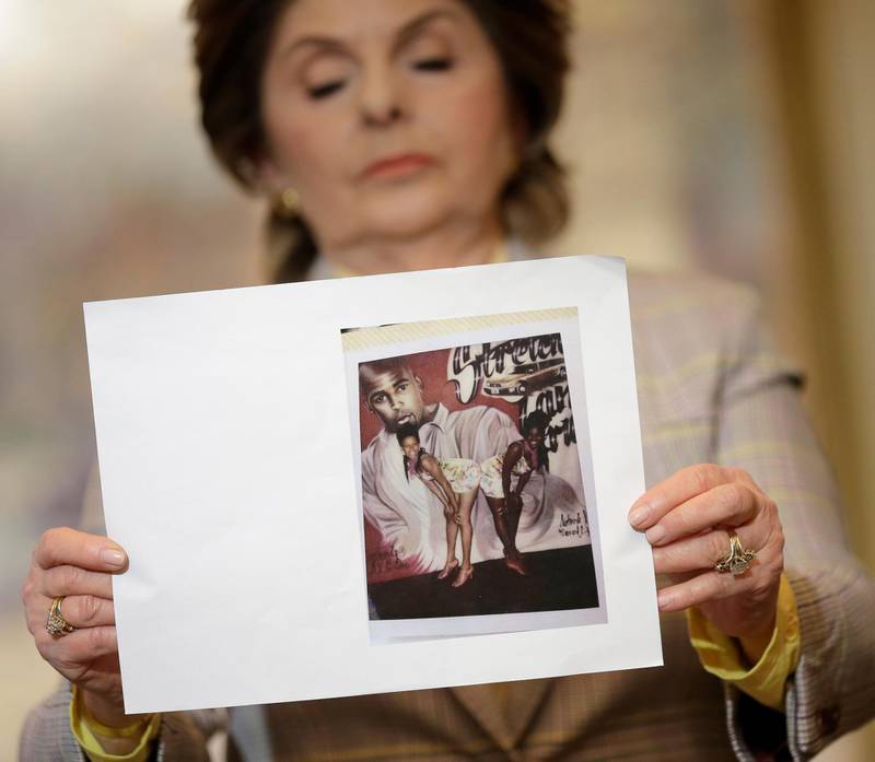 Attorney Gloria Allred holds up a picture of Latresa Scaff, left, and Rochelle Washington, posing in front of a picture of R. Kelly, on the night they claim they became victims of his sexual advances during a news conference in New York, Thursday, Feb. 21, 2019. Scaff and Washington are accusing musician R. Kelly of sexual misconduct on the night they attended a concert of his while they were teenagers.(AP Photo/Seth Wenig)