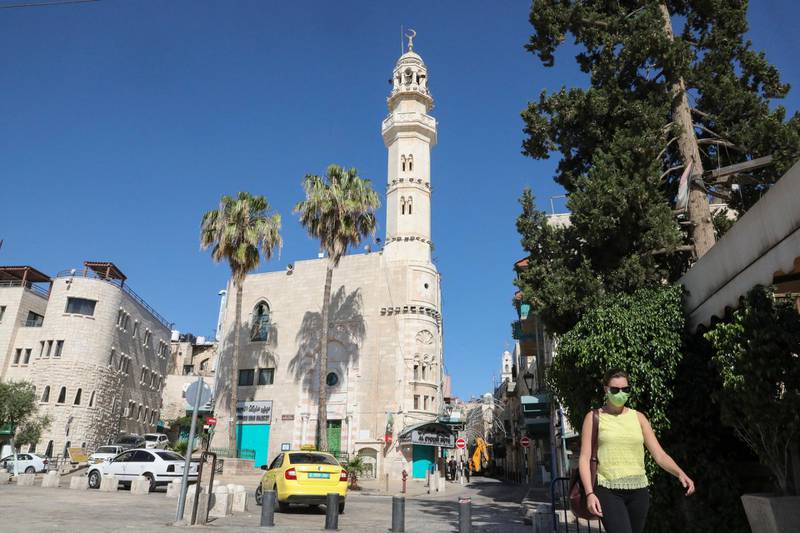 A woman walks near the closed Omar Ben Al-Khatab mosque in Bethlehem on June 29, 2020, as a decision to close the city for 48 hours as of 6.00am (0300 GMT) takes effect to contain the spread of coronavirus, after a sharp rise in infections in the occupied West Bank. (Photo by HAZEM BADER / AFP)
