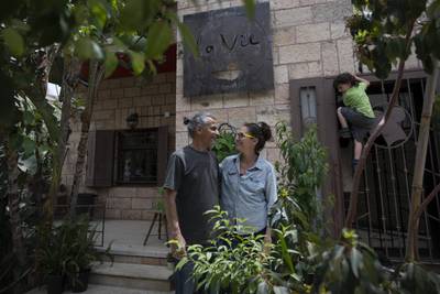 Kenae Totah, 5, plays while his parents Morgan Cooper and Saleh Totah stand in front of their restaurant in the West Bank city of Ramallah.  The Israeli military body in charge of civilian affairs in the occupied West Bank has developed a new policy that would heavily regulate entry into the territory. AP