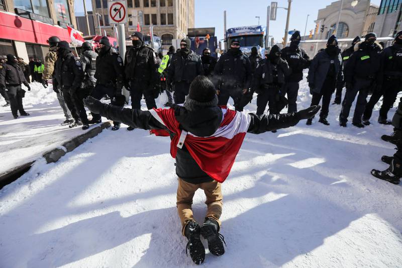 A protester kneels in front of police officers. Reuters
