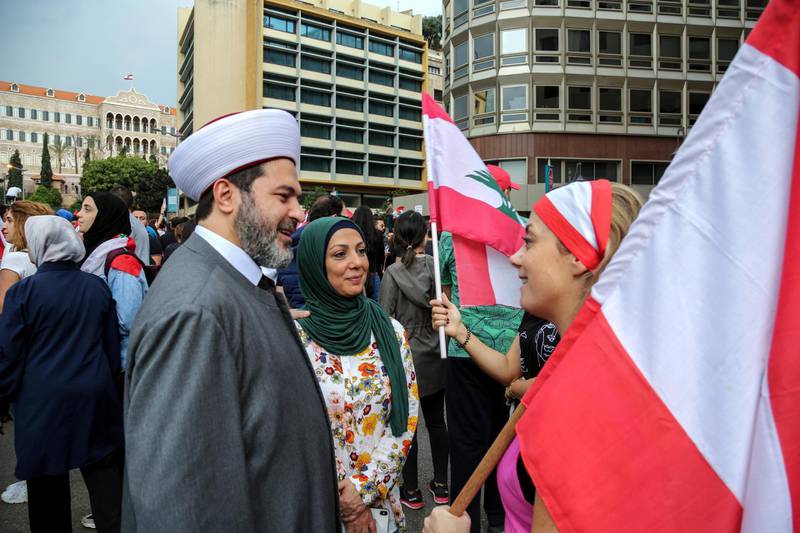 A Sunni cleric chat with a protester carrying Lebanese flags at the seventh day of protest in Beirut, Lebanon.  EPA