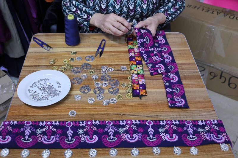An employee embellishes embroidered strips of fabric at the shop in Beit Sahour.