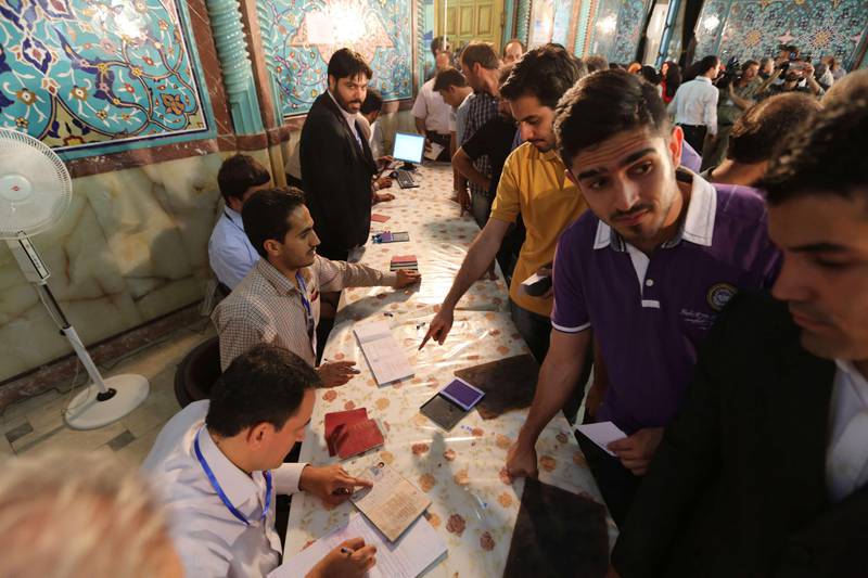 Iranian men show their documents as they vote in the first round of the presidential election at a polling station in Tehran on June 14, 2013. Iranians are voting to choose a new president in an election the reformists hope their sole candidate will win in the face of divided conservative ranks, four years after the disputed re-election of Mahmoud Ahmadinejad. AFP PHOTO/ATTA KENARE
 *** Local Caption ***  341011-01-08.jpg