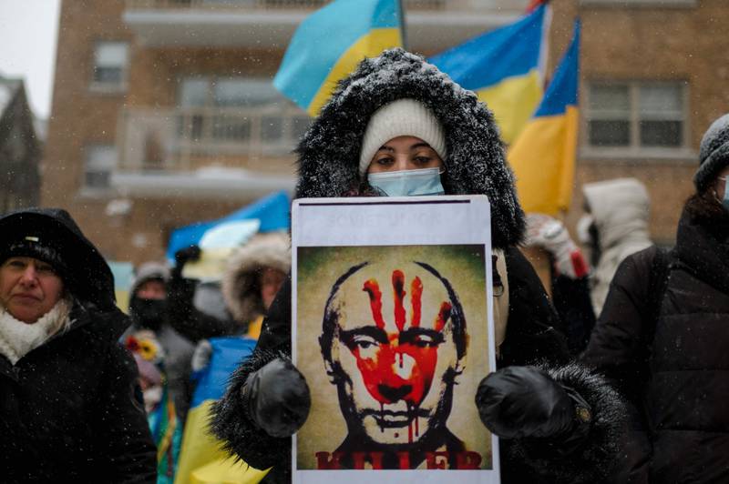 A woman holds a portrait of Russian president Vladimir Putin with a bloody hand on his face as members of the Ukrainian community protest in front of the Consulate General of the Russian Federation. AFP