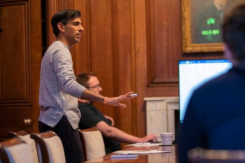 In a grey jumper, white socks and black sandals available for £95 ($131) from Palm Angels, Rishi Sunak works on his speech.