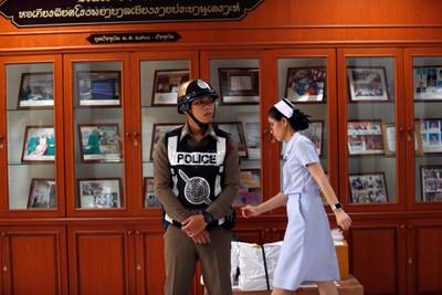 A Thai nurse walks past a police officer during a press conference on the condition of eight boys. EPA