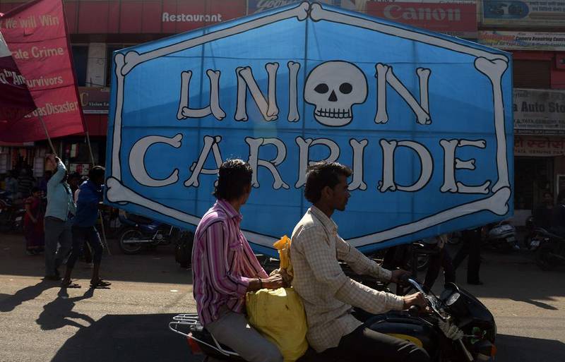 Indian motorists drive past a poster bearing the name of Union Carbide, the company responsible for the gas leak in 1984 which killed at least 15,000 people over the years. Indranil Mukherjee / AFP Photo

