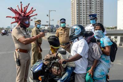 -- AFP PICTURES OF THE YEAR 2020 --

Police inspector Rajesh Babu (C) wearing coronavirus-themed helmet speaks to a family on a motorbike at a checkpoint during a government-imposed nationwide lockdown as a preventive measure against the COVID-19 coronavirus in Chennai on March 28, 2020. - One minute they're dancing in the street in comical coronavirus helmets, the next they're seen beating people for flouting a nationwide lockdown -- Indian police have played good cop, bad cop in a bid to halt the spread of coronavirus. The streets of India's cities have been largely deserted for more than a week of the government's 21-day lockdown -- no mean feat in a country of 1.3 billion people famed for their flexible attitude towards authority. (Photo by Arun SANKAR / AFP)