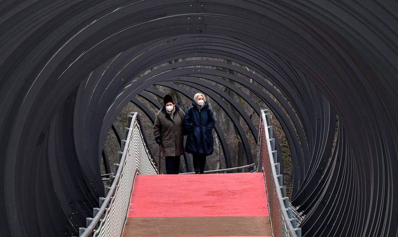 People wear protective face masks due to the coronavirus pandemic, as they walk over a bridge during the lockdown in Oberhausen, Germany, Monday, Jan. 11, 2021. (AP Photo/Martin Meissner)