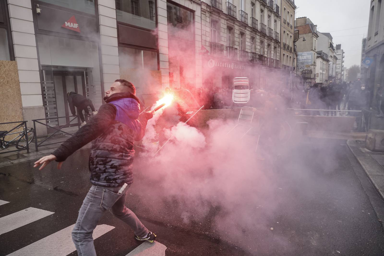 A man throws a flare towards riot police in Rennes, as protests continue across France over pension reforms and the rising cost of living. AP