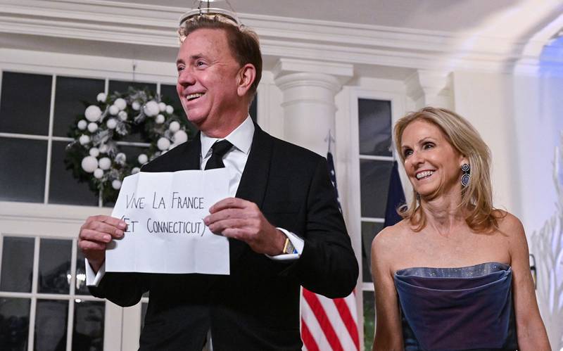 Governor of Connecticut Edward Lamont and wife Annie Lamont hold up a sign for Mr Macron. AFP