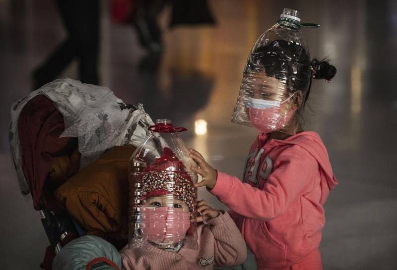 Chinese children wear plastic bottles as an improvised protective mask while waiting to check in to a flight at Beijing Capital Airport in Beijing, China. Getty Images