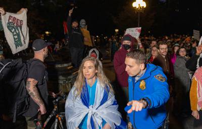 A pro-Israel counter protester wrapped in the Flag of Israel is escorted away from a vigil organised by NYU students in support of Palestinians in Washington Square Park in New York. AFP