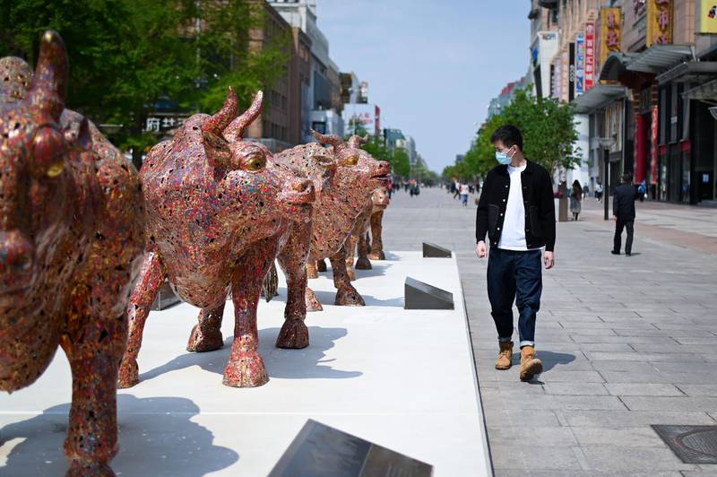 A man walks past bronze bull statues along a business street in Beijing. AFP