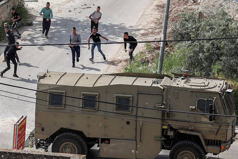 Stones are thrown at a passing Israeli military vehicle during the unrest. AFP