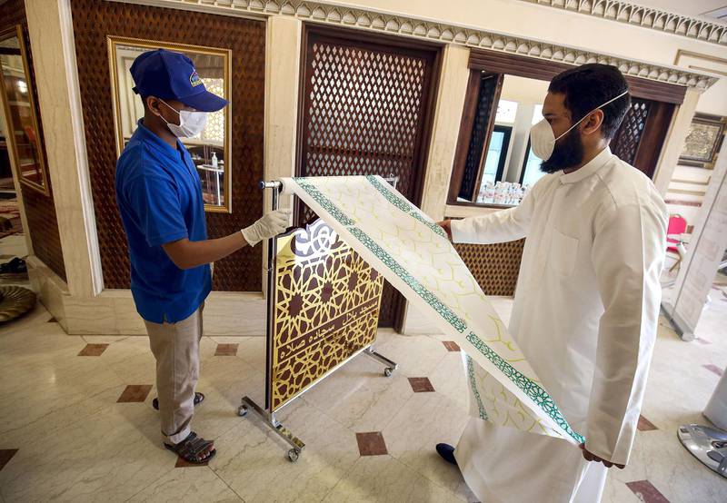 A worshipper pulls a sheet of paper to fashion as a disposable prayer mat for noon prayers at a mosque in Kuwait City.   AFP